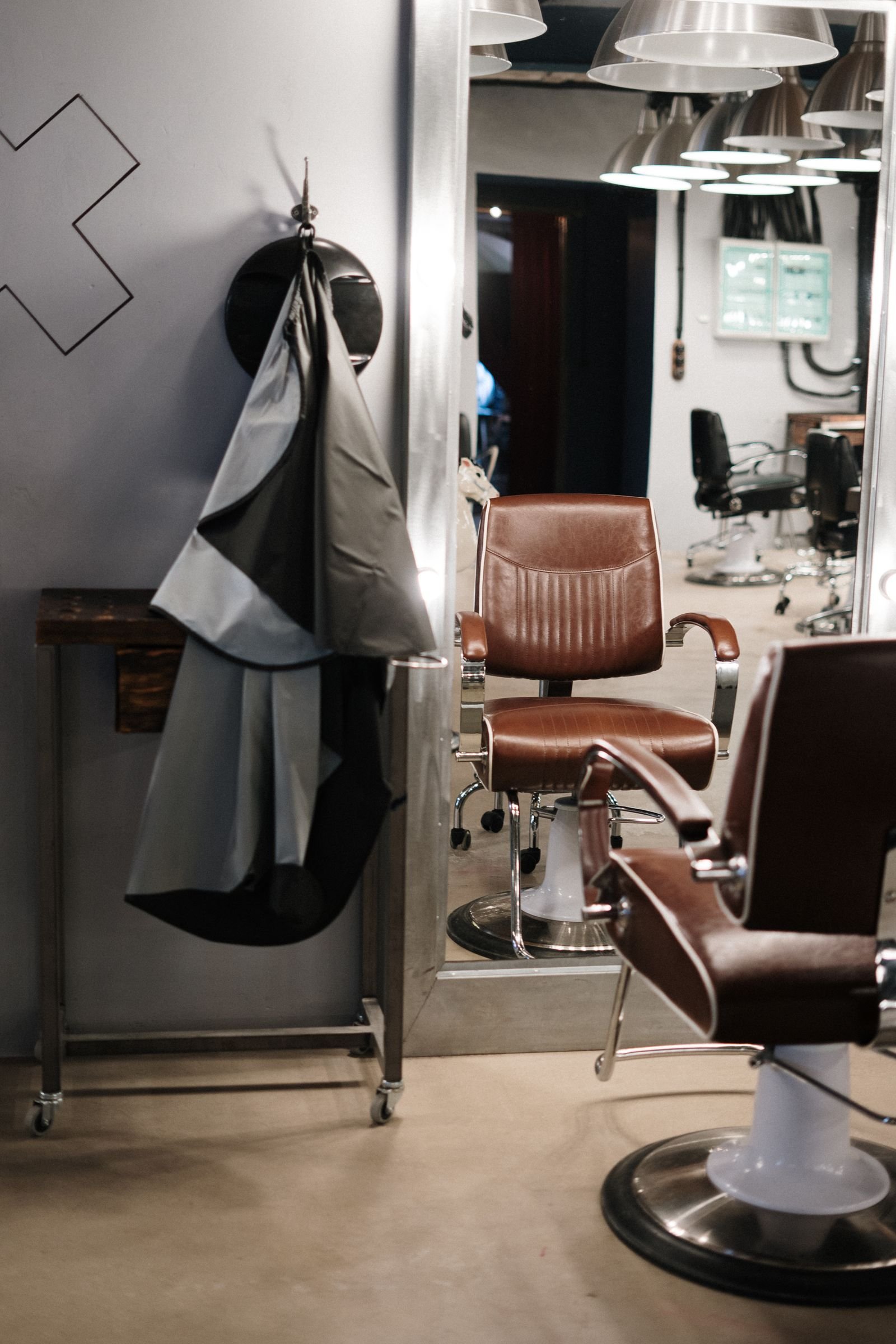 Fauteuils de coupe en cuir brun à piètement chromé, devant un miroir