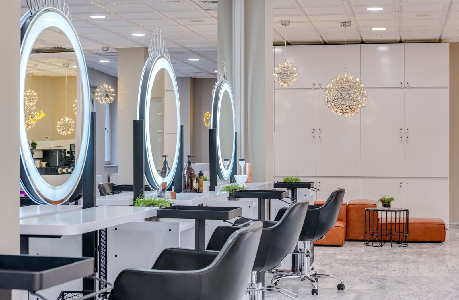 Postes de coiffure alignés, fauteuils noirs et miroirs LED ronds